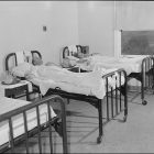 Black and white photo of two patients laying in hospital beds.