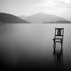 Black and white photograph of a chair out on a lake