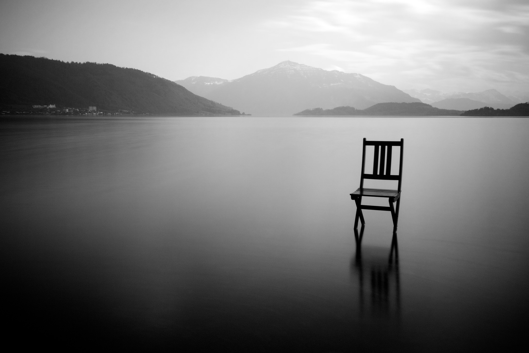 Black and white photograph of a chair out on a lake