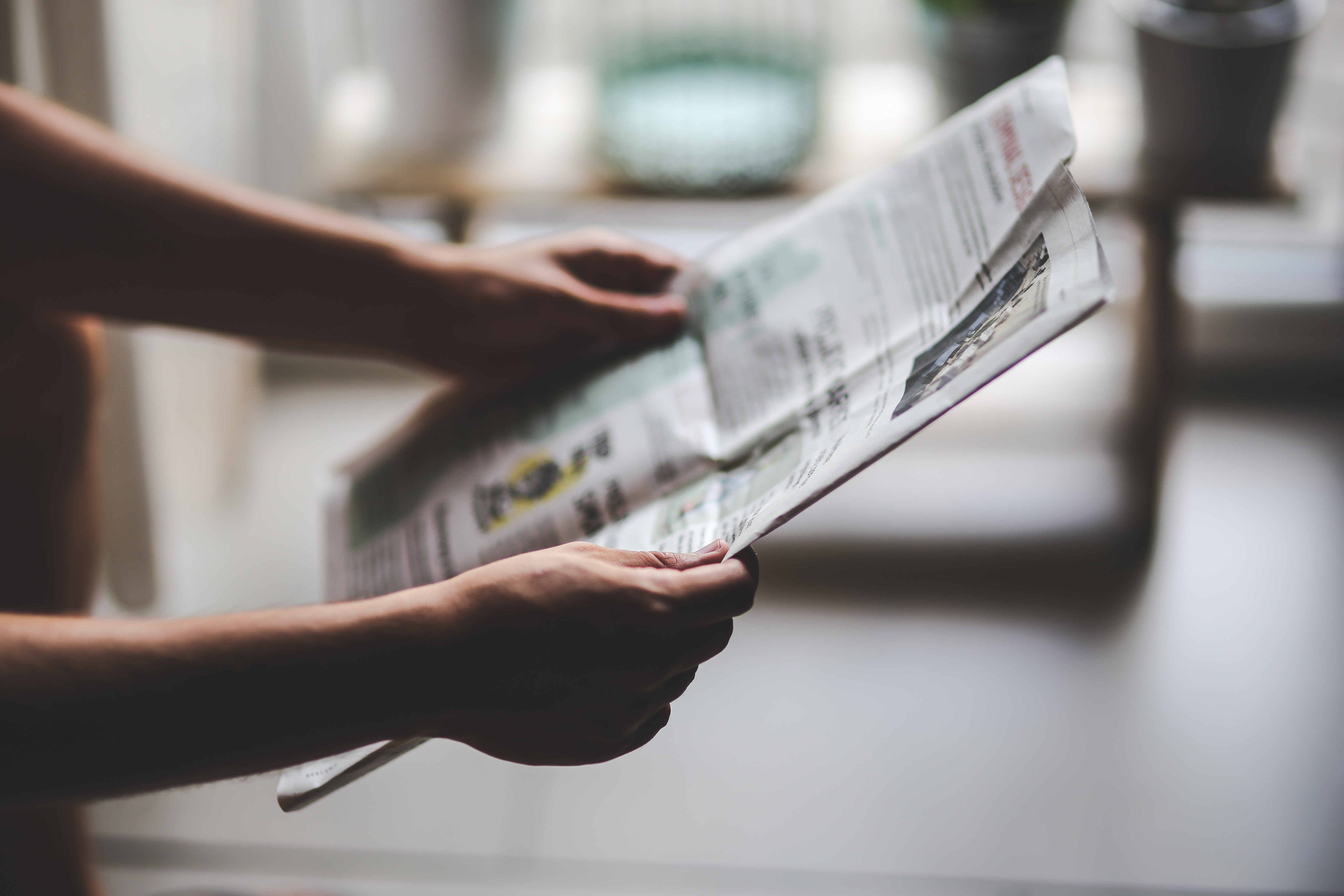 Image of a person's hands holding a newspaper