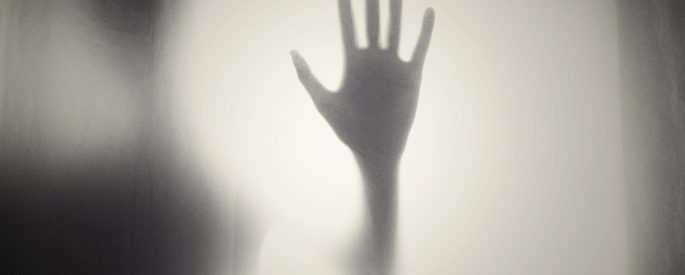 A hand is pressed against foggy glass.