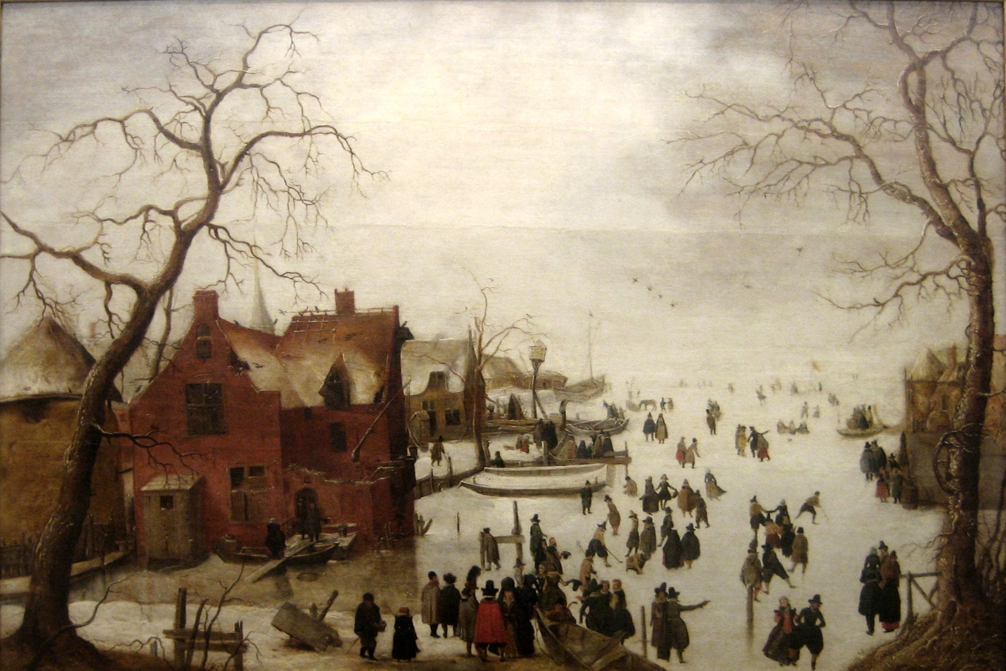 An oil painting of a village, with skaters on an ice covered pond and people walking under bare trees. While the landscape is baren, the painting feels crowded.