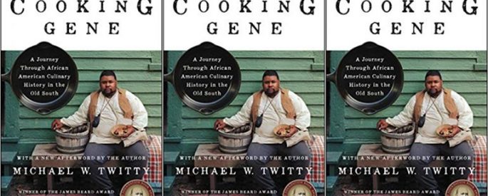Cover of "The Cooking Gene" by Michael Twitty, with a photo of the author sitting in front of a green building holding a bowl of food