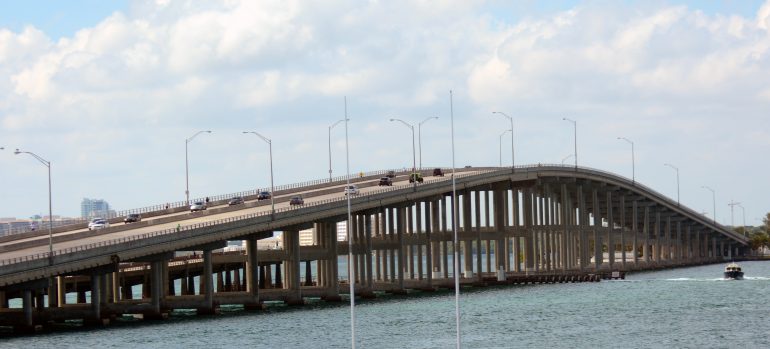A large curved bridge over the ocean with lots of cars on it