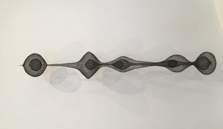 Wire form sculpture piece by artist Ruth Asawa showing a variety of shaped wire forms within and around other wire forms, interconnected and overlapping in one horizontal line