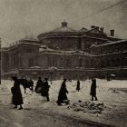 a black and white photograph of a Russian theatre in winter with people walking around