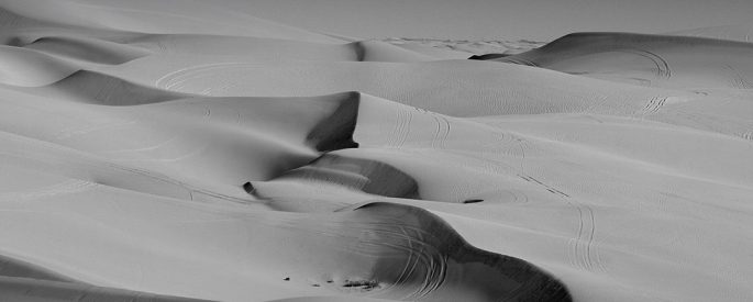 a black and white photograph of and endless panorama of sand dunes