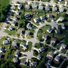 photograph of a sprawling suburb at an aerial view--houses connected by winding roads against bright green grass