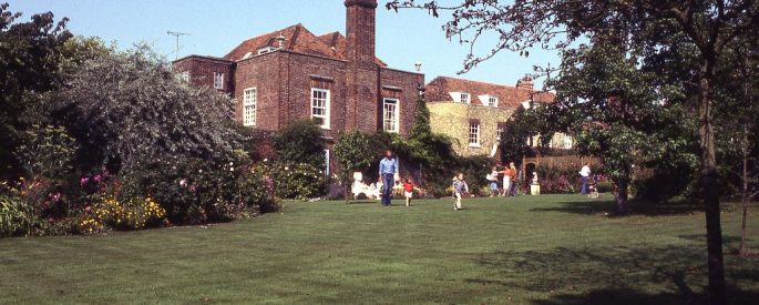 a film photograph of the back of the Lamb House--a small family appears to be playing on the lawn