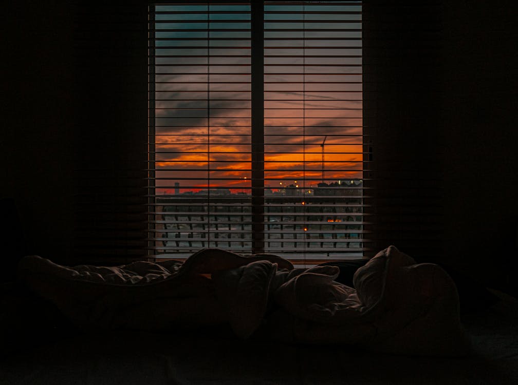 image of a crumpled bed sheet in front of a a window--the sun is rising outside