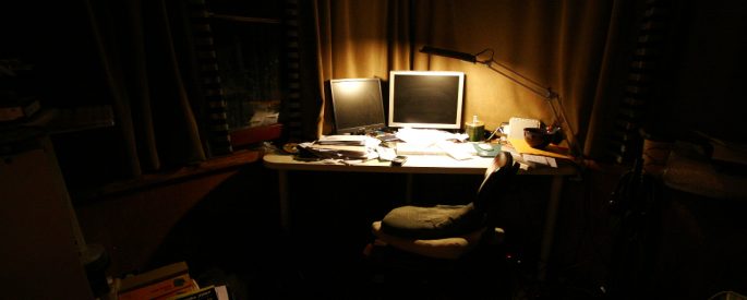 photo of a desk illuminated only by a small lamp