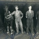 black and white vintage photograph of three coal miners and a mule in a mine shaft