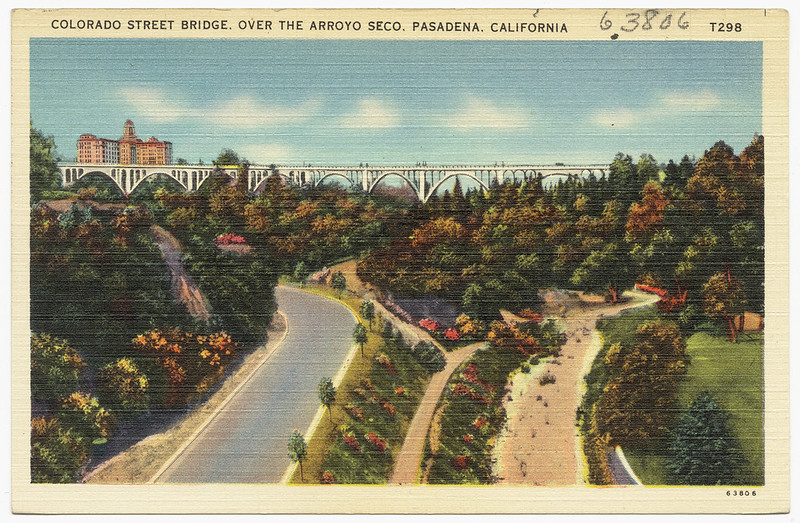 a vintage photograph showing a paved road and a dirt road or river bed running parallel under a bridge in California
