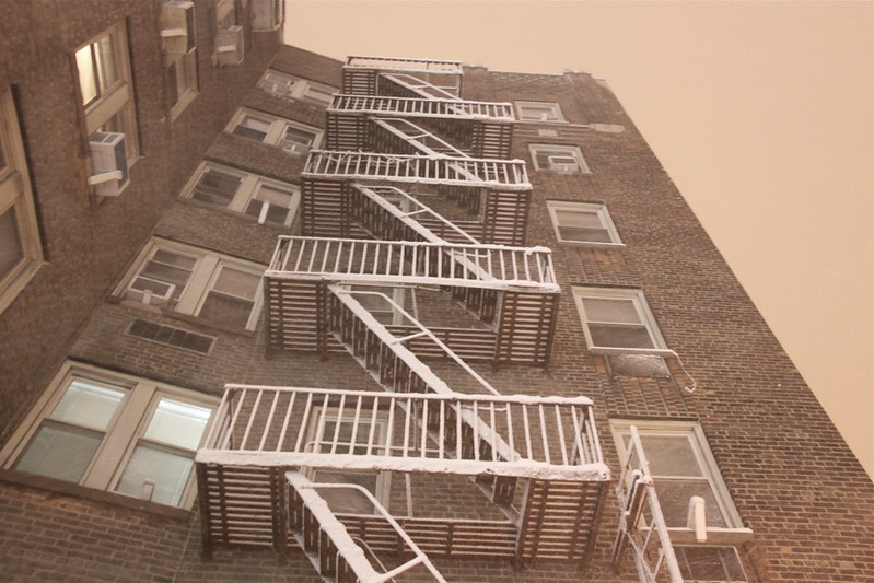 a photograph of the side of an apartment building and its fire escapes, seen from below